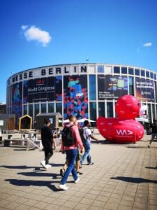 Man sieht die Berliner Messe und einige Besucher der #WeAreDevs. Außerdem die rote Quietsche-Ente, das Wahrzeichen der Messe